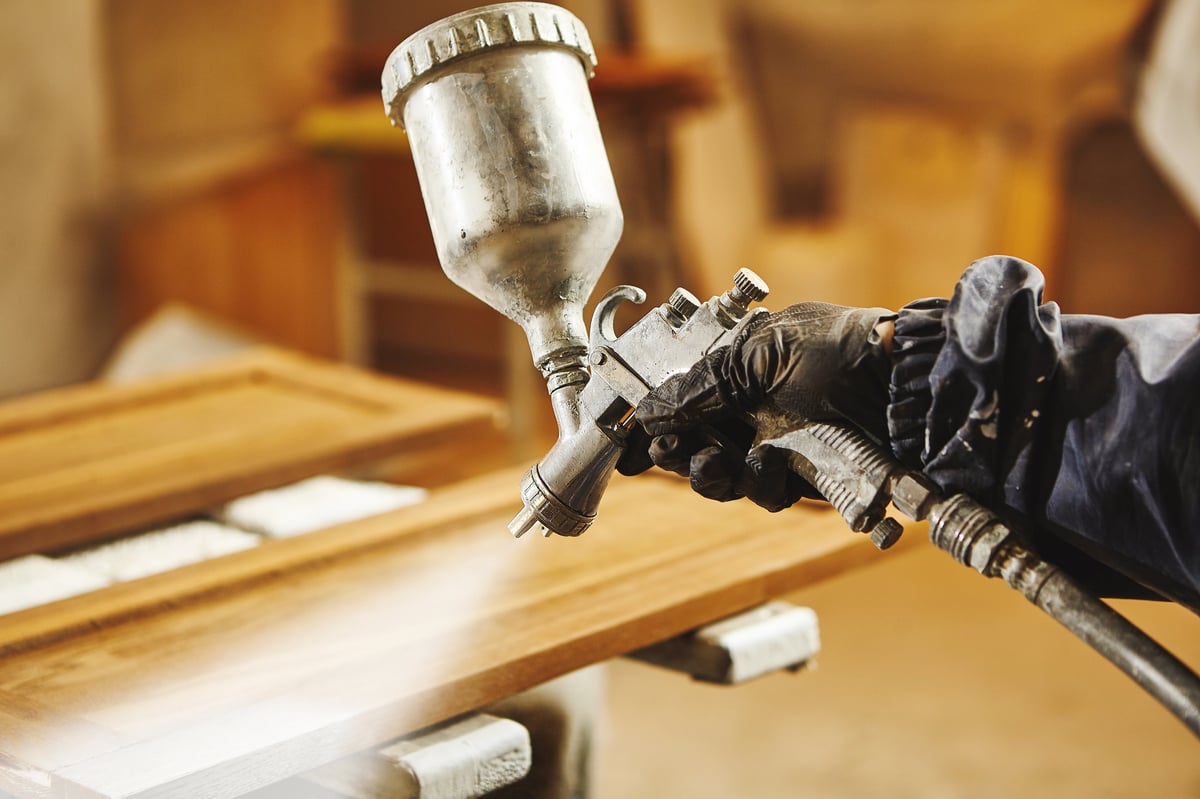 Spray painting wooden cabinets in workshop